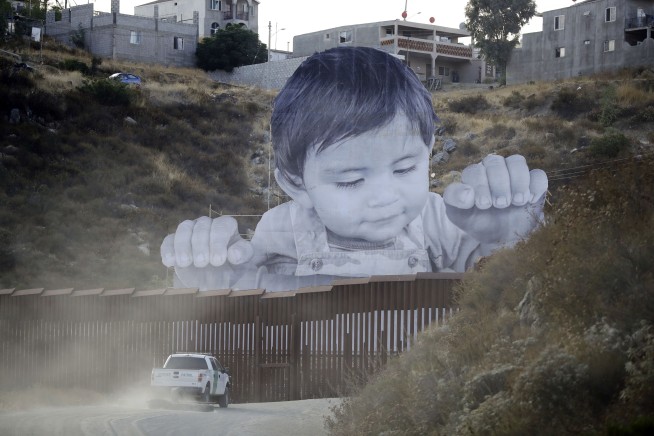 Giant portrait of toddler peers over US-Mexico border wall