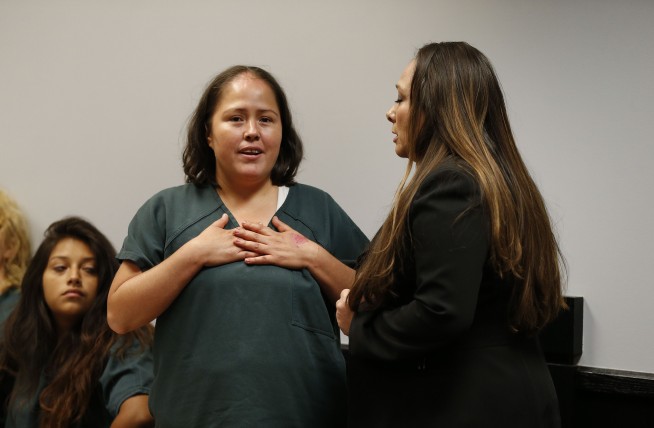 Woman charged in slayings of 4 children, dad smiles in court